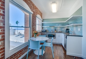 A modern kitchen with a brick wall, a large window, and a view of the sky.