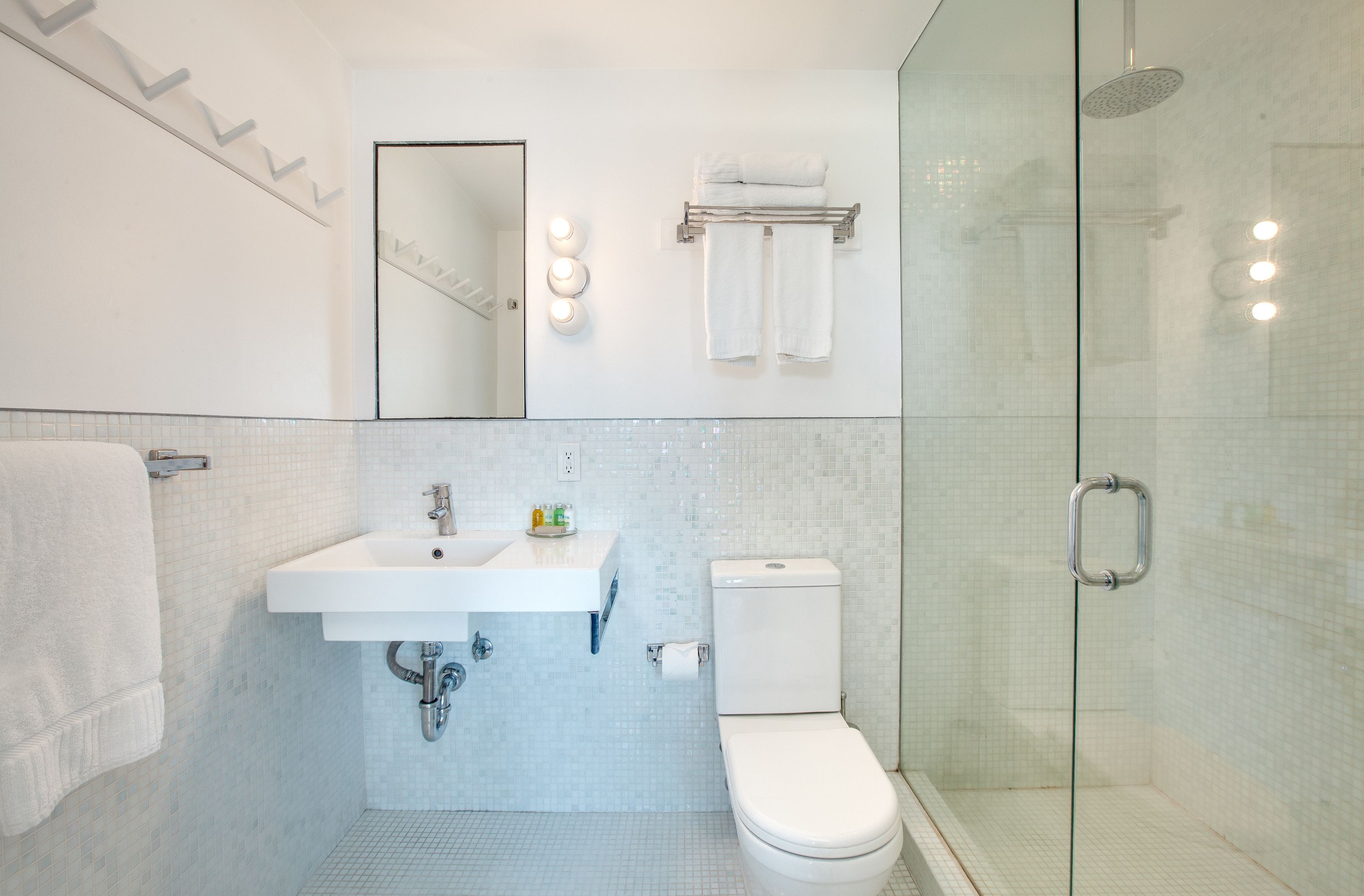 A modern bathroom with a glass-enclosed shower, a white sink, and a toilet.