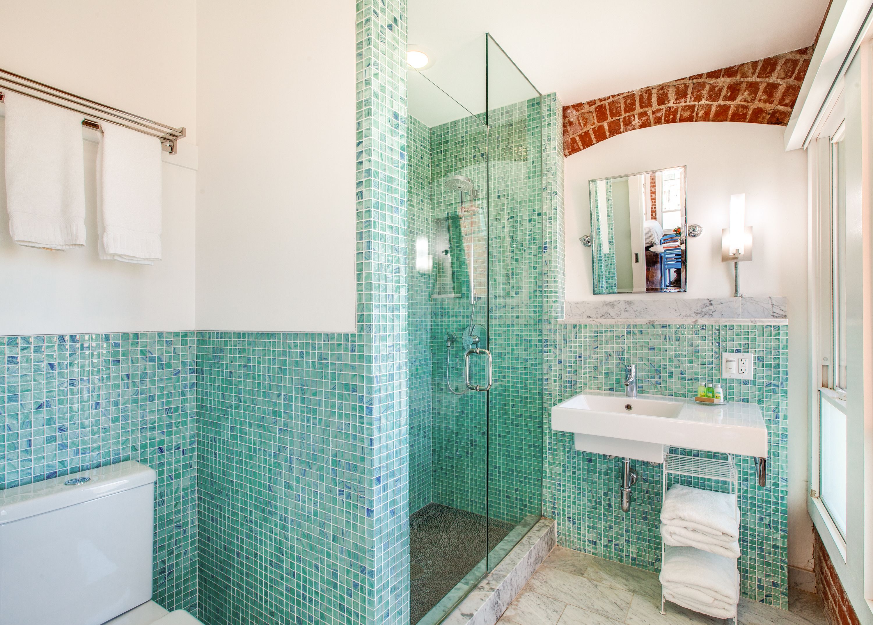 A bathroom with a glass-enclosed shower, a white sink, and a mirror above it.
