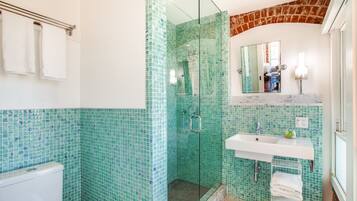 A bathroom with a glass-enclosed shower, a white sink, and a mirror above it.