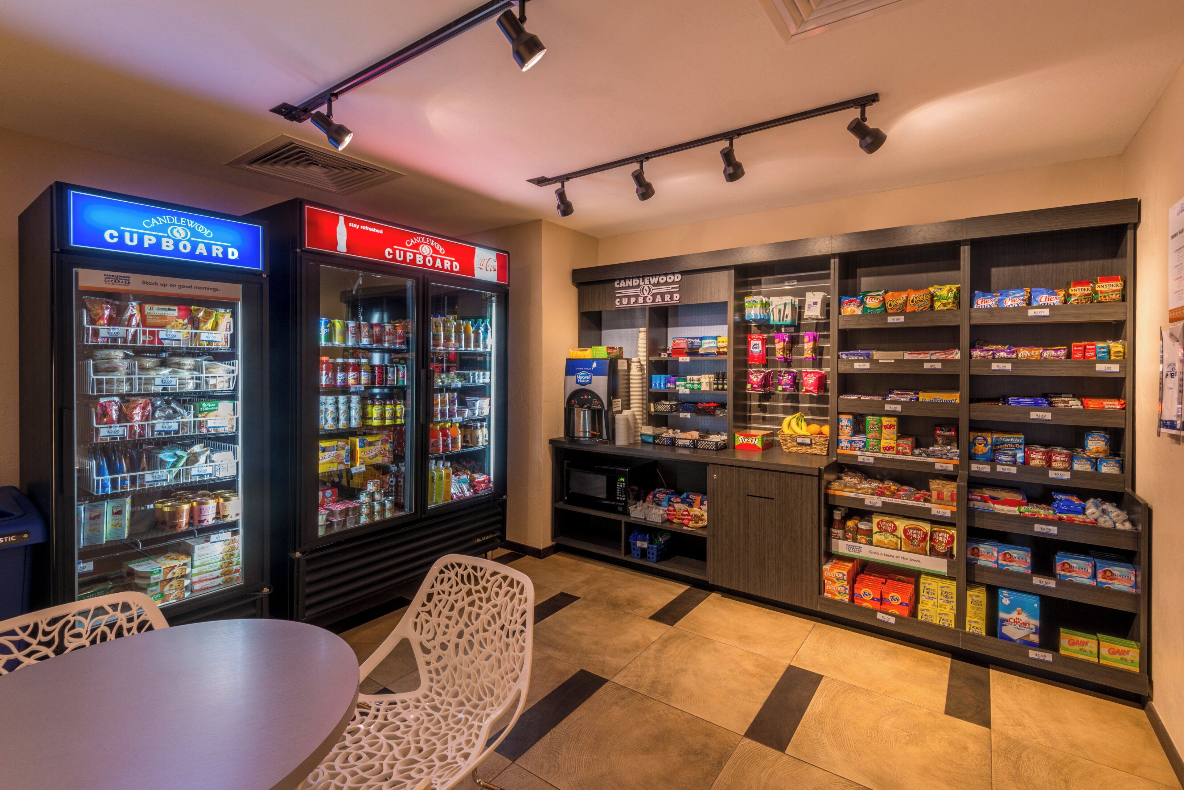A snack bar area with vending machines, shelves stocked with snacks, and a seating area with a table and chairs.
