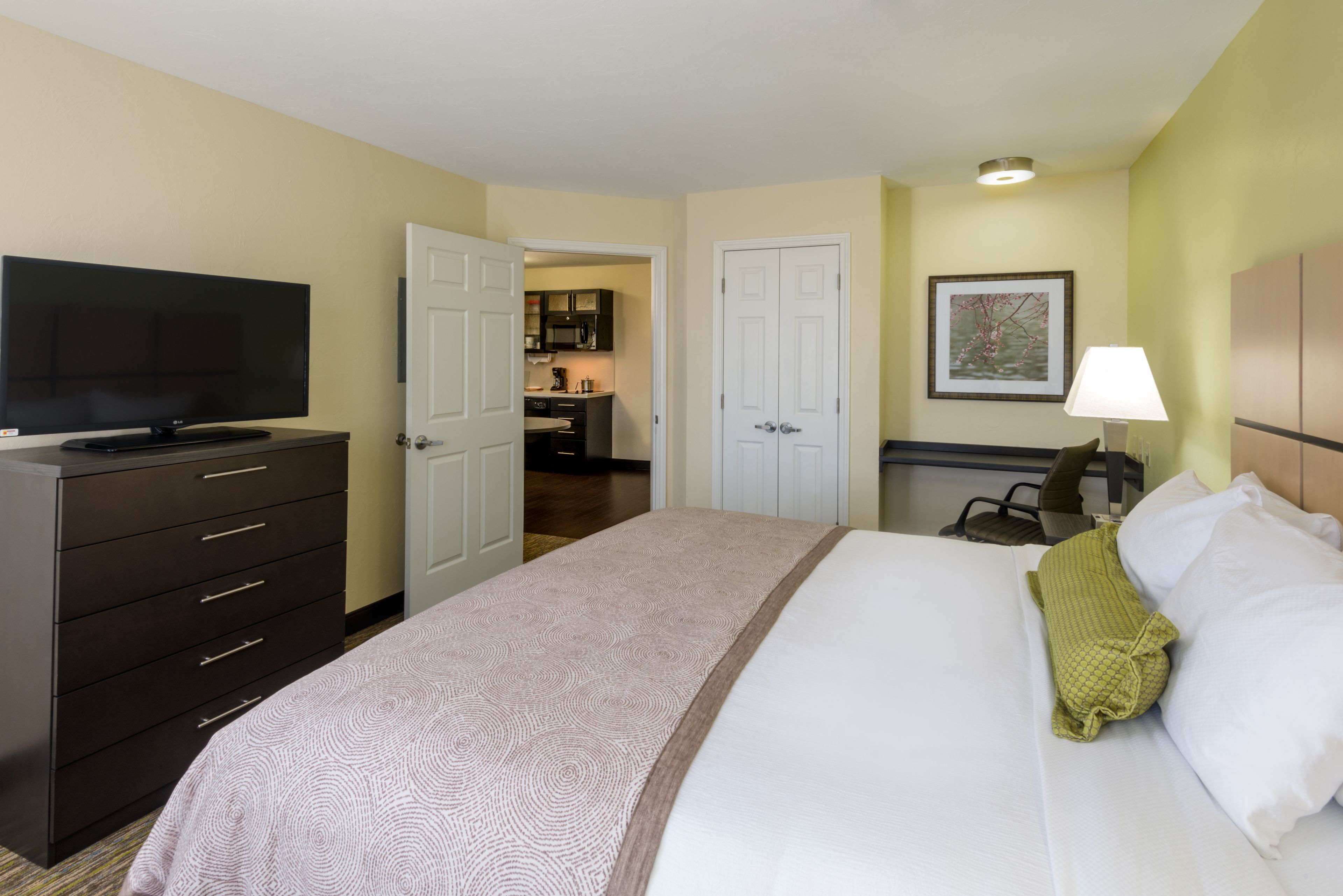 A hotel room with a bed, a TV, a desk, and a chair.