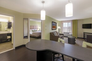 Una habitación de hotel con cama, escritorio, silla, televisor y ventana con cortinas.