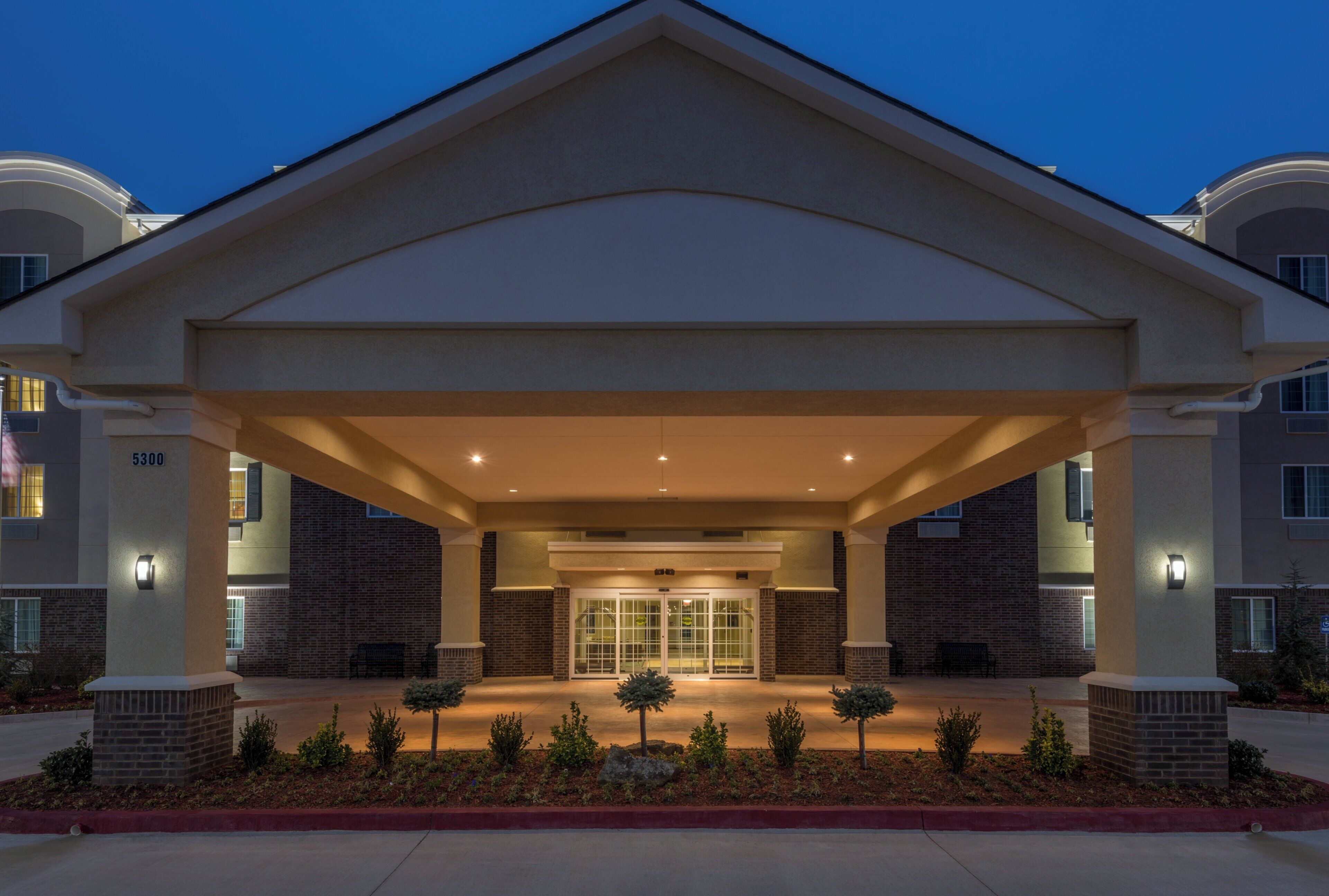 A hotel entrance with a covered walkway, brick facade, and a number sign.