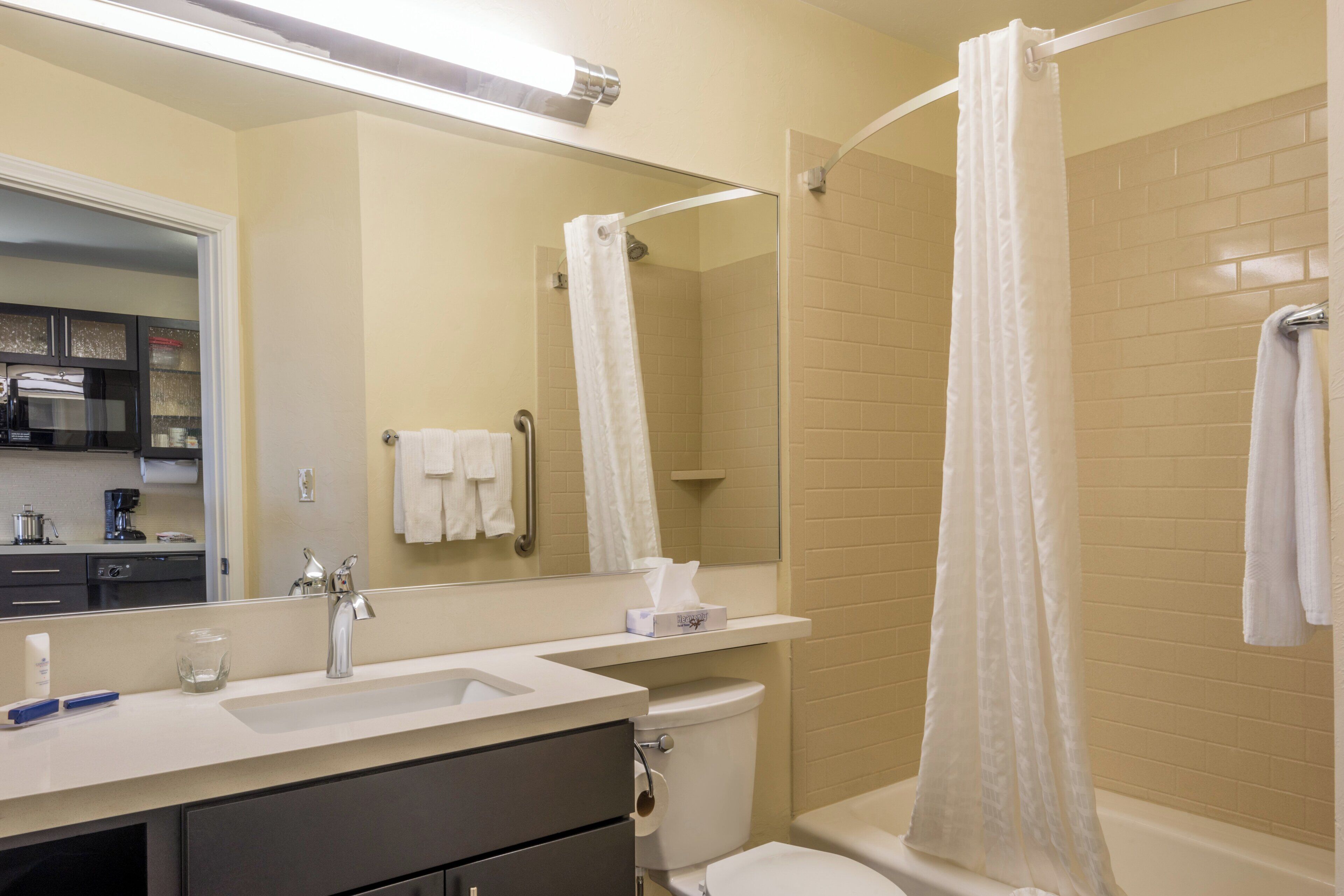 A bathroom with a shower, toilet, sink, and a mirror.