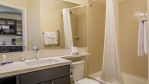 A bathroom with a sink, mirror, toilet, and shower curtain.