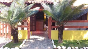 Un camino lleva a un edificio con entrada de azulejos, rodeado de palmeras y un muro amarillo.