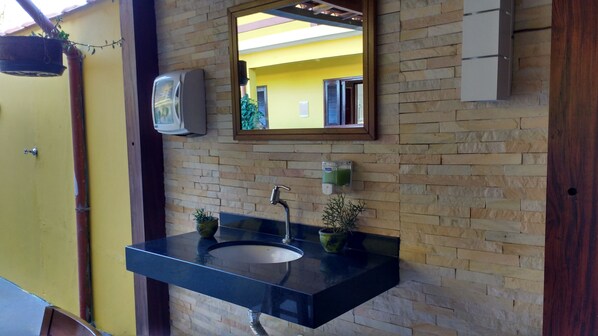 A bathroom with a black sink, a mirror, and a stone wall.