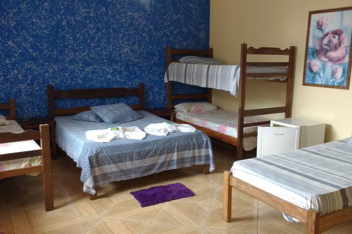 Habitación tipo dormitorio con literas, un refrigerador pequeño y una alfombra morada.
