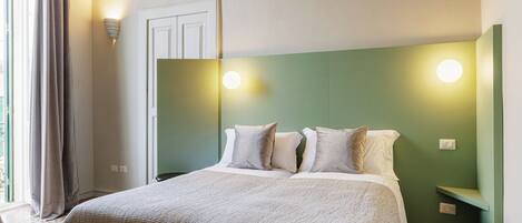 Habitación de hotel con una cama grande, una pared de acento verde y un piso estampado.