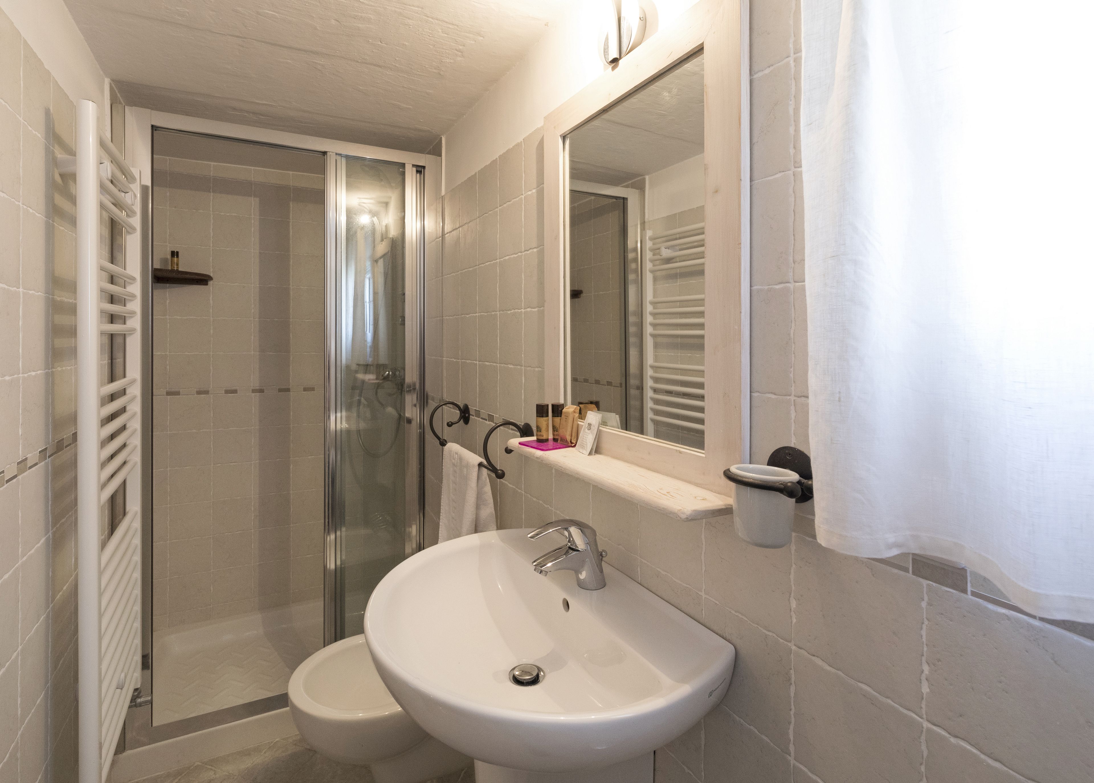 Un baño con ducha de vidrio, lavamanos y espejo.