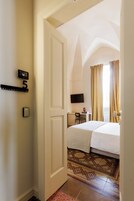 Habitación de hotel con cama, escritorio, silla, televisor y cámara en la pared.