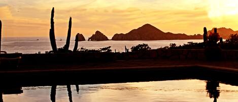 Una vista tranquila del atardecer sobre aguas calmadas, con montañas lejanas y cielo despejado.