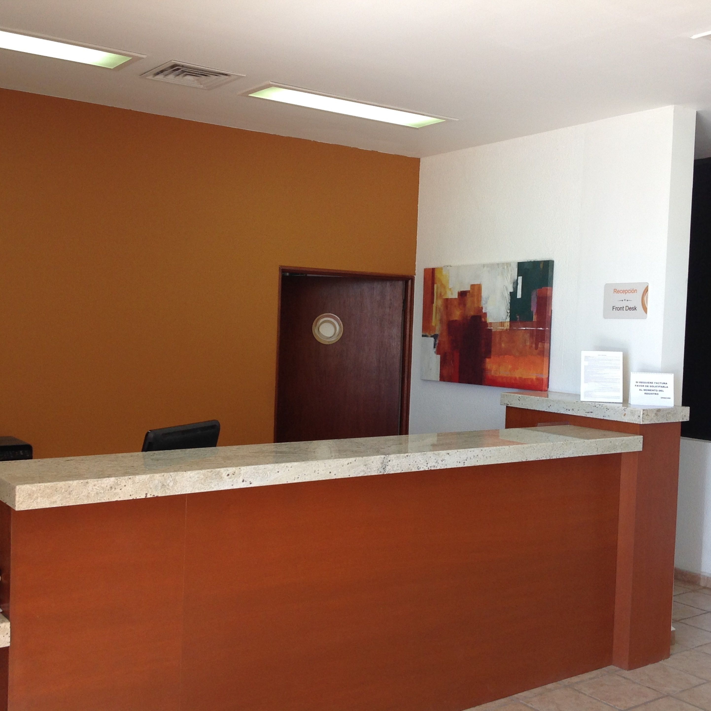 Una mesa de recepción con mostrador marrón y una puerta al fondo.