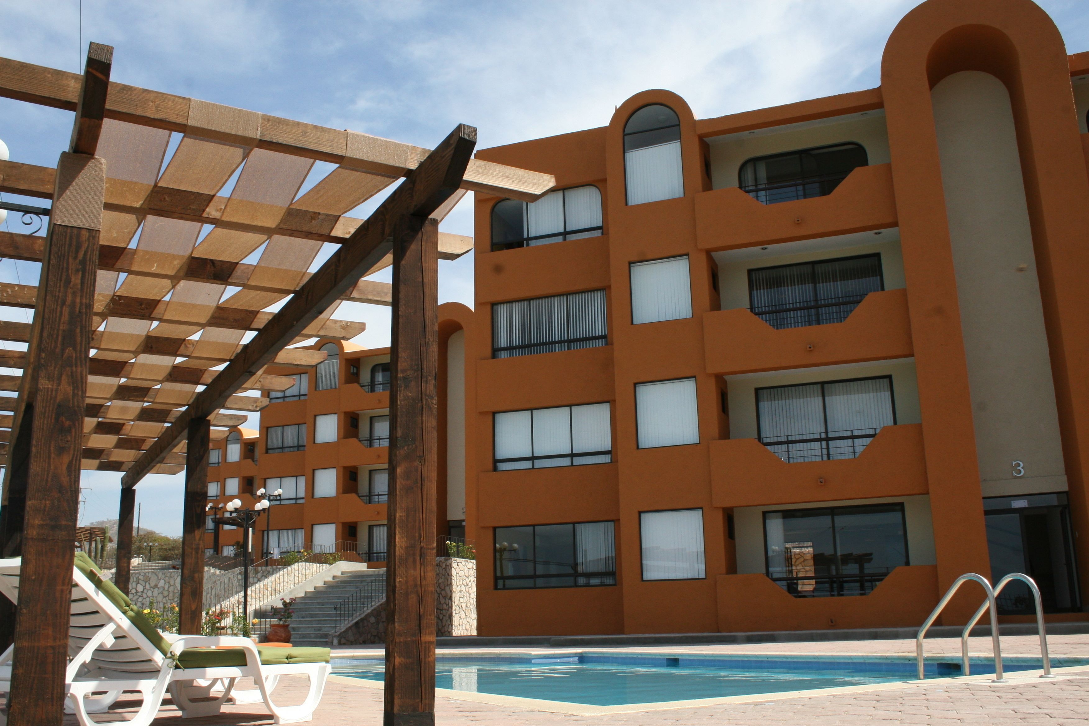 A multi-story building with balconies and a pool area.