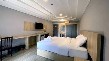 A hotel room with a bed, a desk, a television, and a mirror.