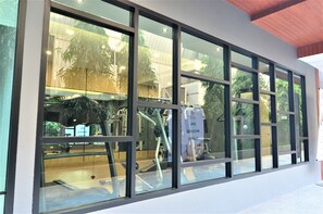 A modern building with large windows, a visible gym area, and a sign indicating a spa. - Tara Garden (Bangkok)
