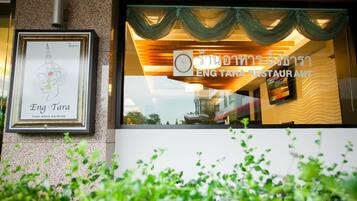 A restaurant window with a sign for Eng Tara Thai Cuisine, framed artwork, and a view of the cityscape.