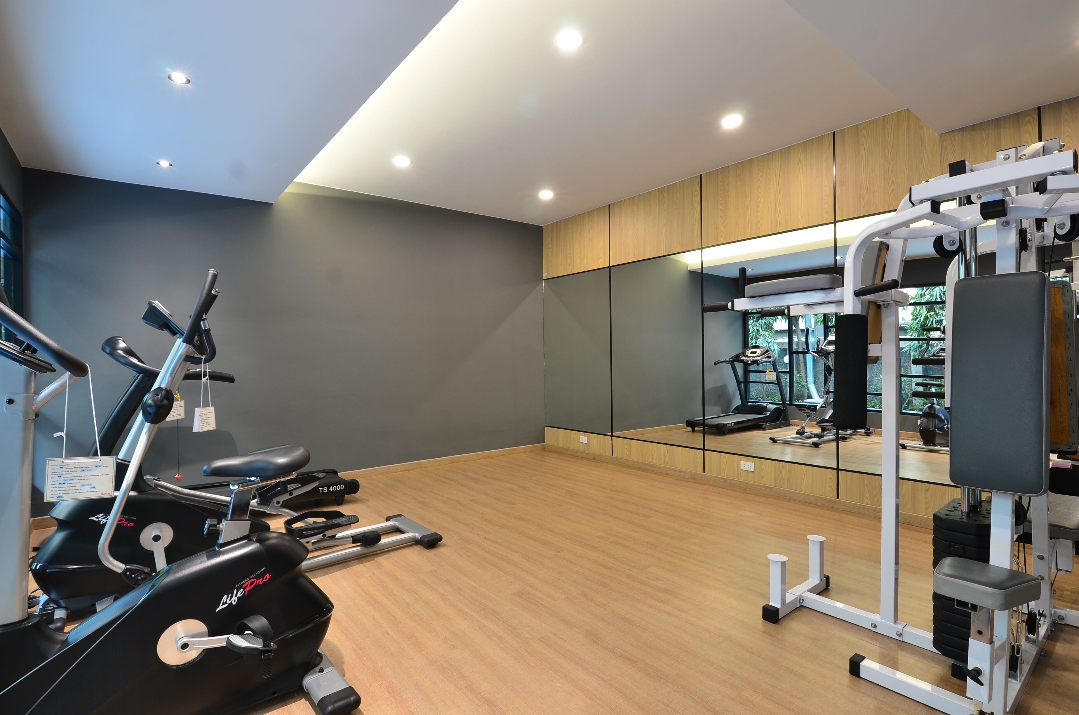 A modern gym with cardio machines, free weights, and a mirrored wall.