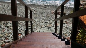 Een houten trap die naar een strand leidt met helderblauw water.
