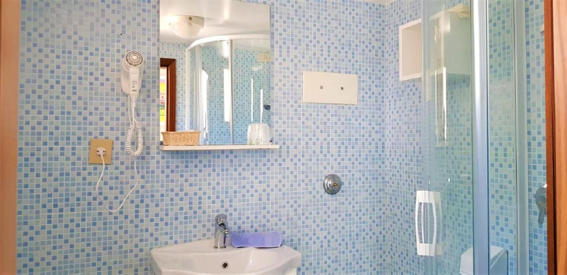 A bathroom with a sink, mirror, and shower.