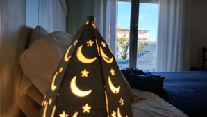 Habitación de hotel con una cama, una luz nocturna con diseños de luna y estrellas, y vistas de edificios a través de la ventana.