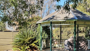 A gazebo with a wooden deck and a covered barbecue area.