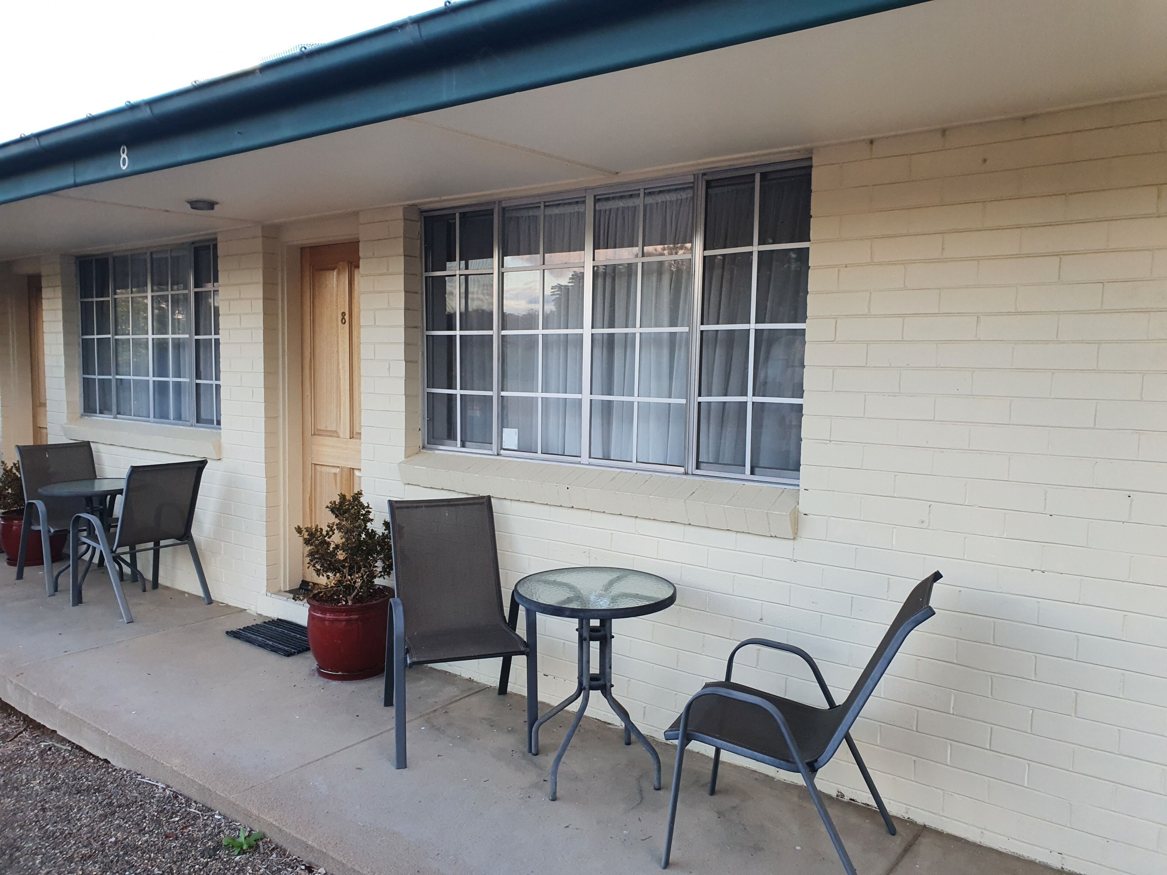 A motel with a covered patio area featuring two tables and four chairs.