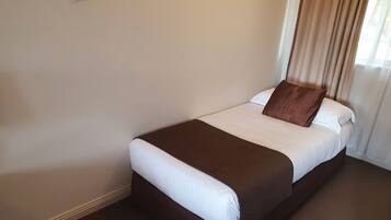 A neatly made bed with a brown headboard and white bedding in a hotel room.