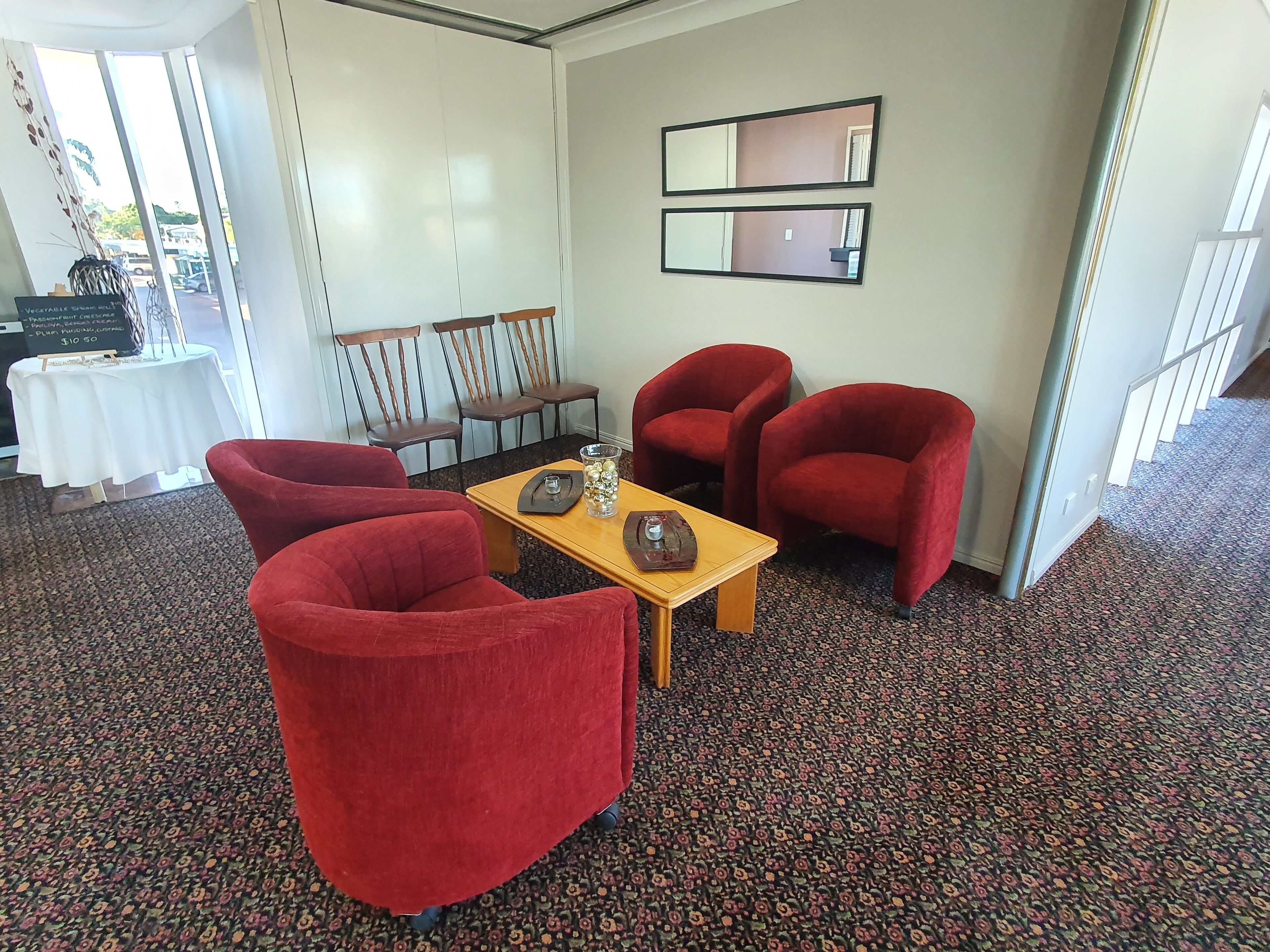 A room with red chairs, a wooden table, and a mirror on the wall.