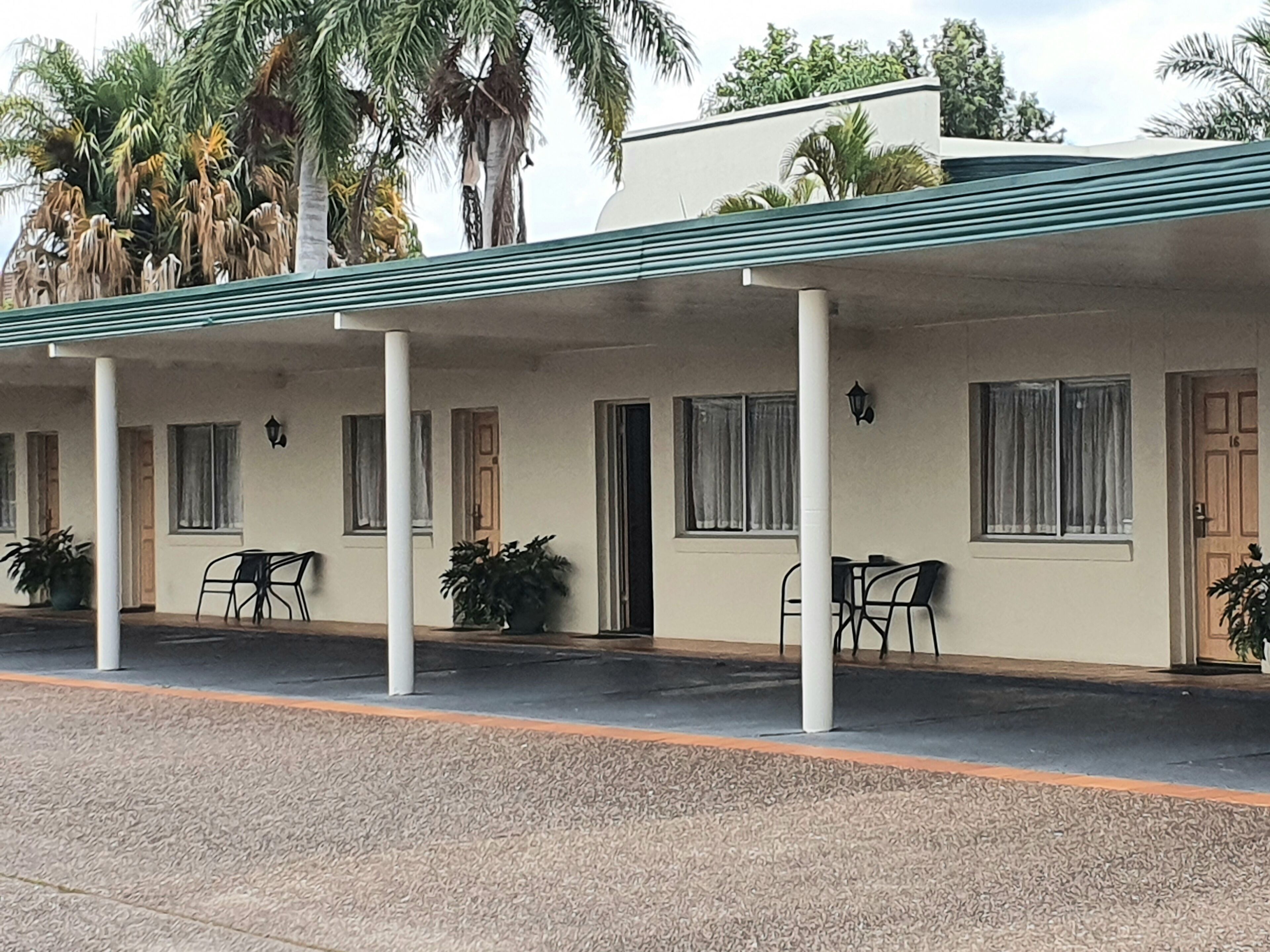 Um motel com varanda coberta, várias janelas e plantas em vasos.