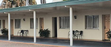 Um motel com varanda coberta, várias janelas e plantas em vasos.