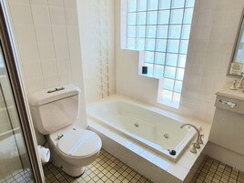 Un baño con inodoro, bañera y ventana de celosía.