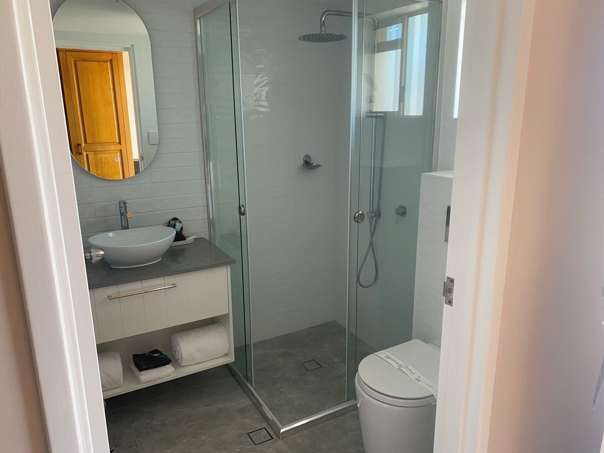 A modern bathroom with a glass-enclosed shower, a white sink, and a toilet.