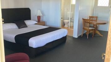Ett hotellrum med en säng, ett skrivbord, en stol och ett badrum.