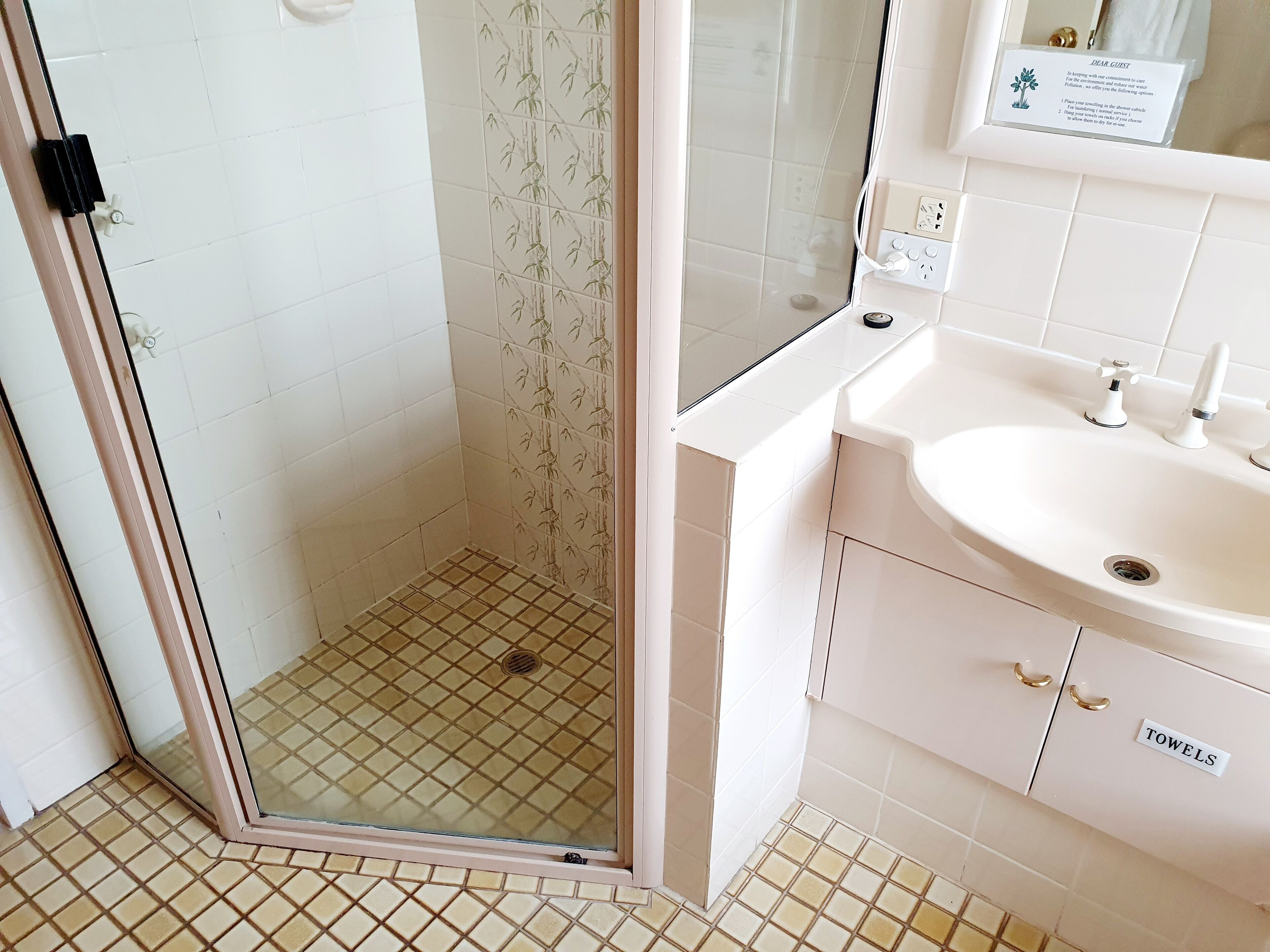 A bathroom with a shower area, a sink, and a towel rack labeled "TOWELS".