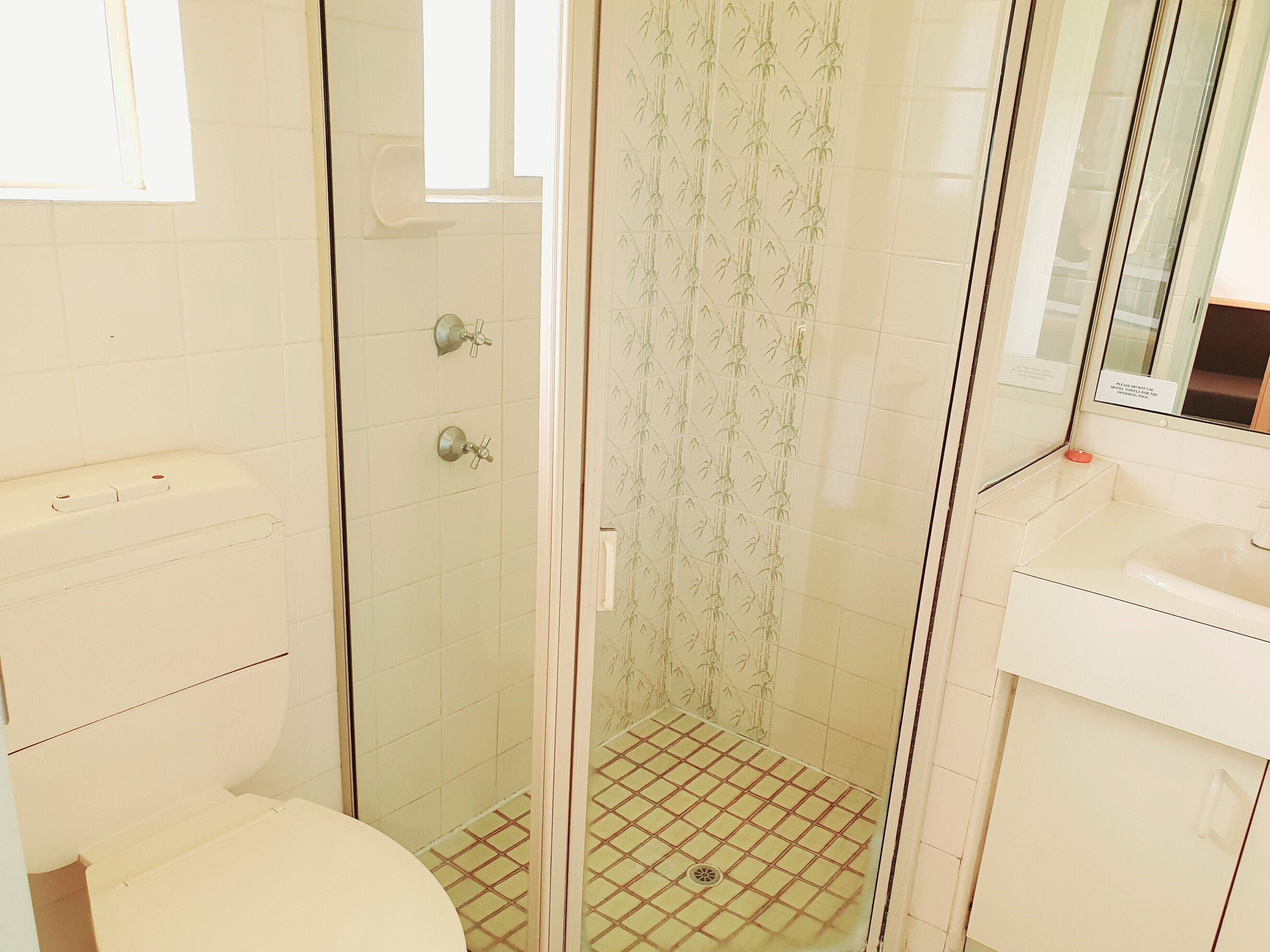 A bathroom with a toilet, a shower with a glass door, and a sink.