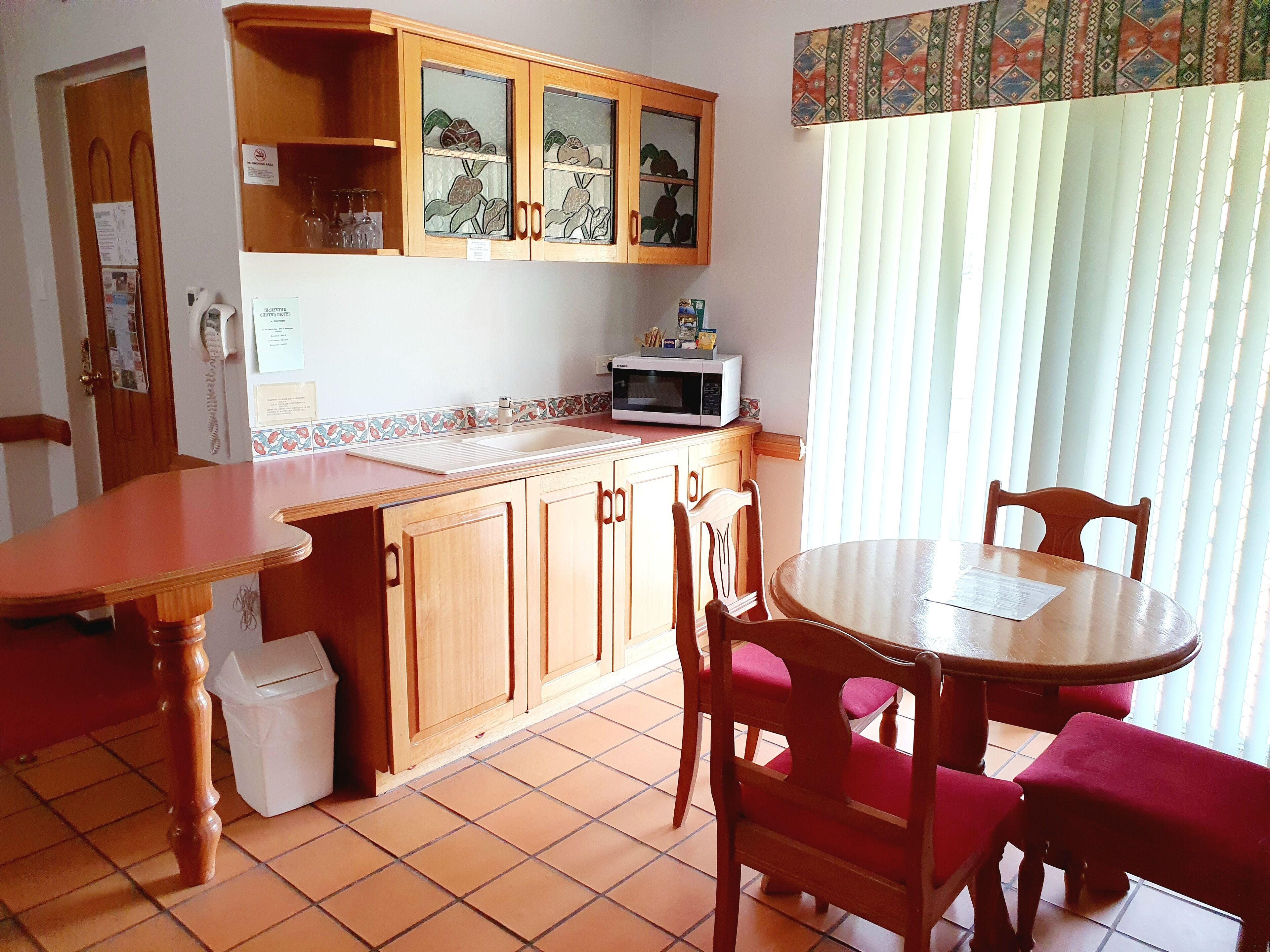 A kitchen with wooden cabinets, a microwave, and a dining area with a table and chairs.