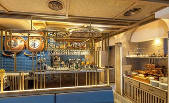 A bar area with wooden barrels, a variety of bottles, and a seating area with a blue bench.