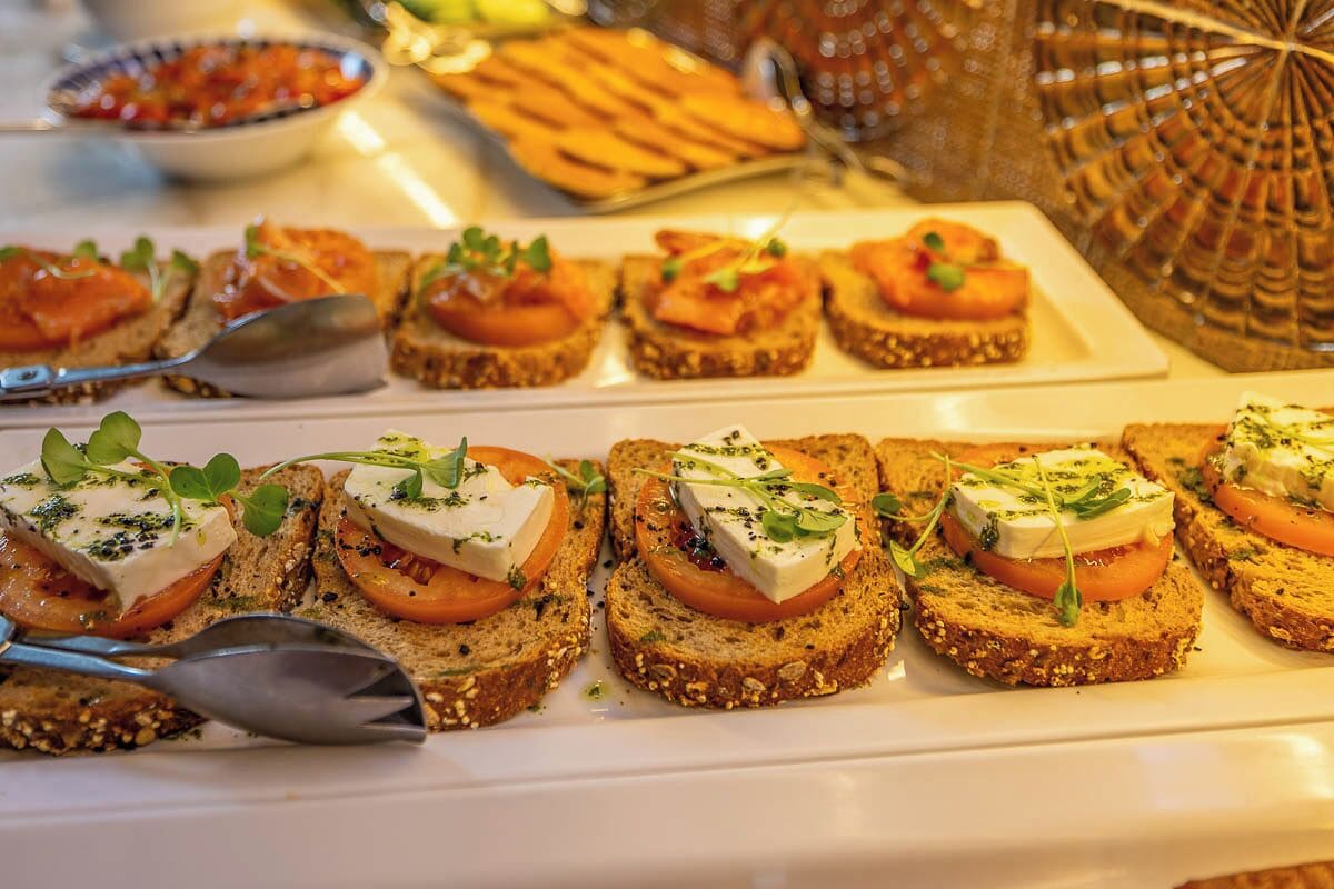 A buffet with various food items including toast with cheese and tomato, and other dishes in the background.