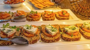 A buffet with various food items including toast with cheese and tomato, and other dishes in the background.