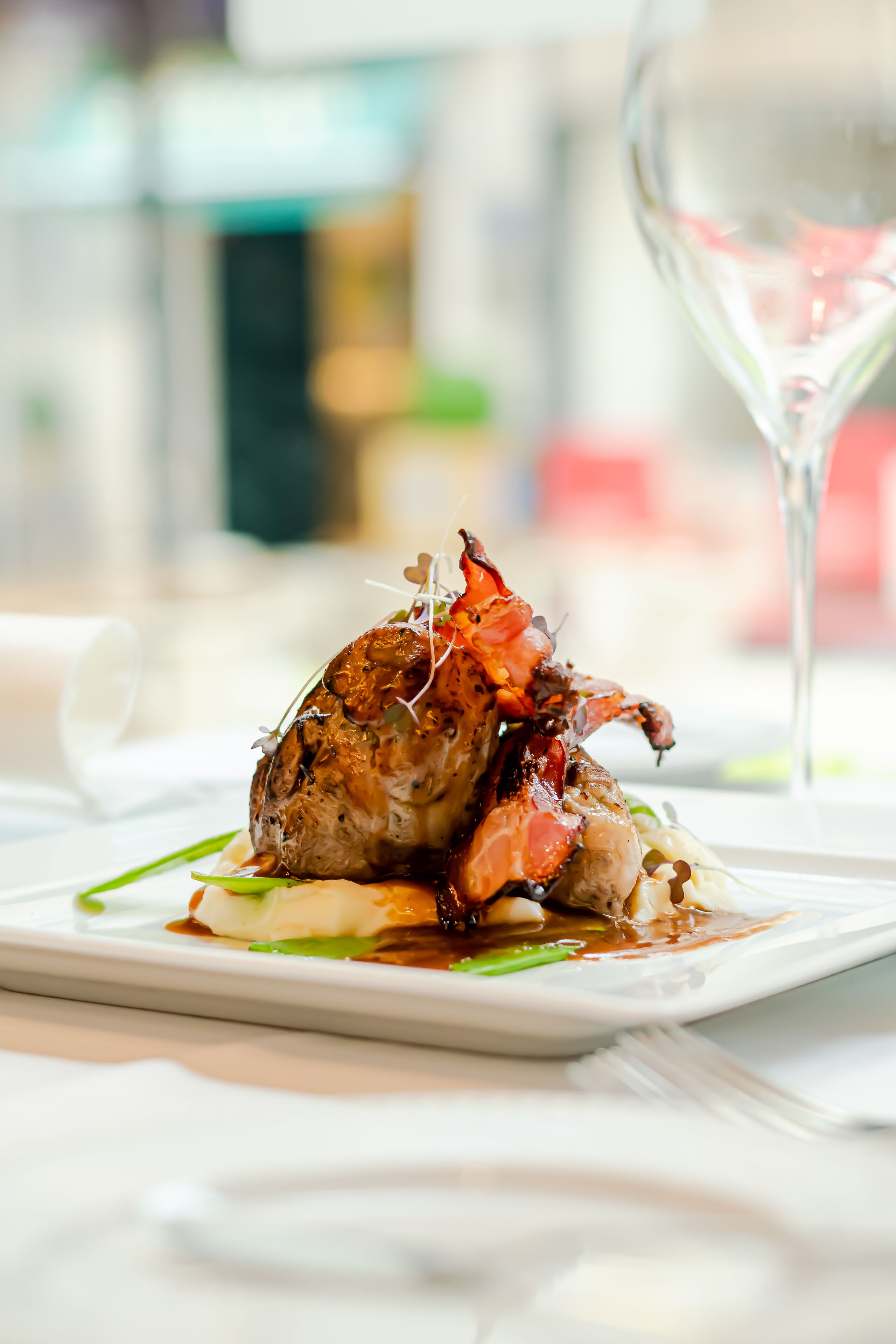 A plate of food with a lobster tail, green vegetables, and sauce, on a white tablecloth.