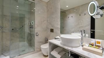 Un bagno moderno con cabina doccia in vetro, lavabo bianco e uno specchio grande.