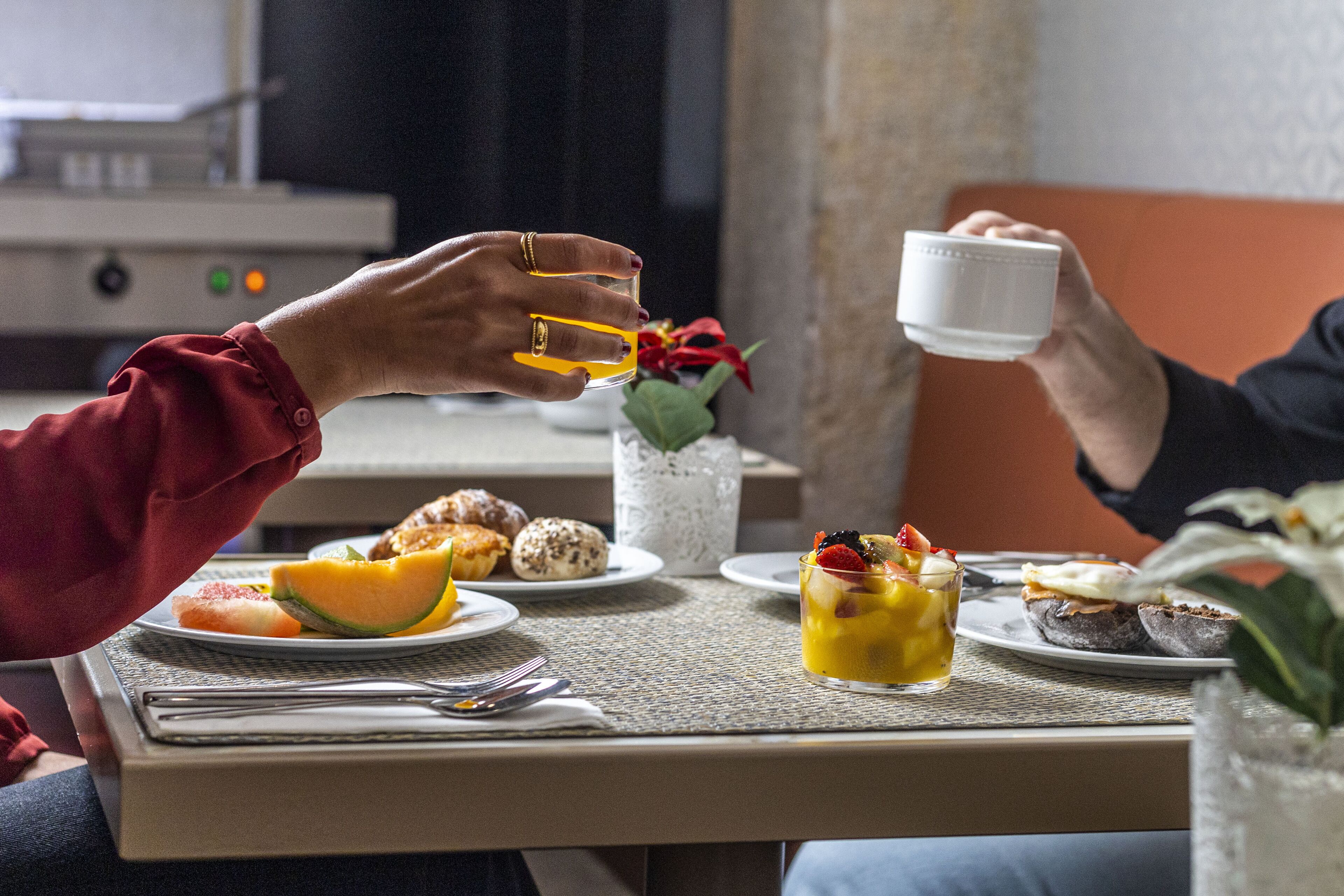 A dining table with plates of food, a glass of juice, and a white cup.