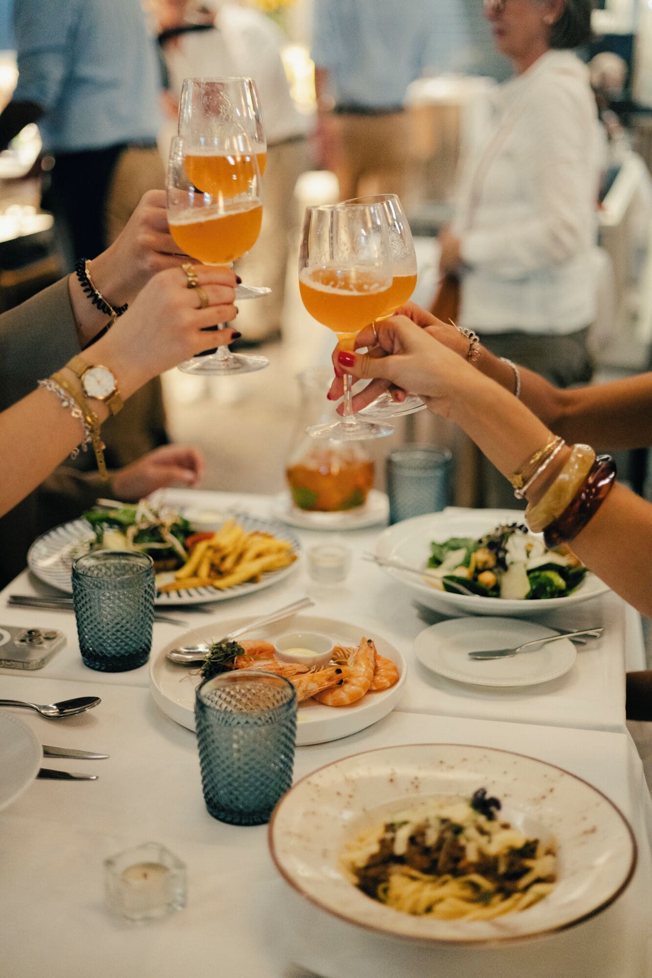 A dining table with plates of food, glasses of a beverage, and cutlery.