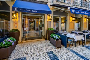 Hotel Santa Justan ulkonäkö: sininen markiisi, ulkona oleva istuinalue ja ruukuissa olevia kasveja.