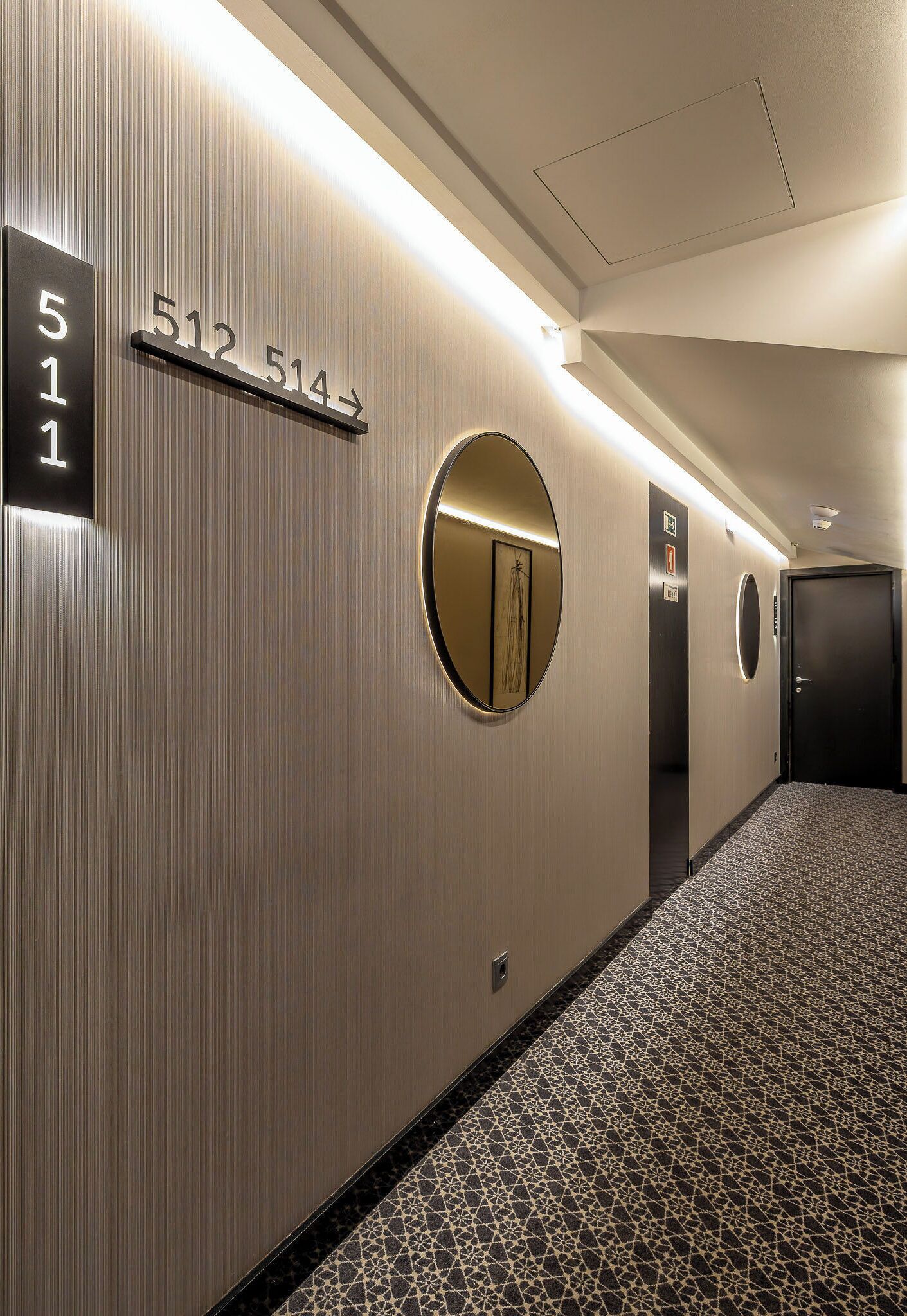 A hotel hallway with a number sign, a mirror, and an elevator.