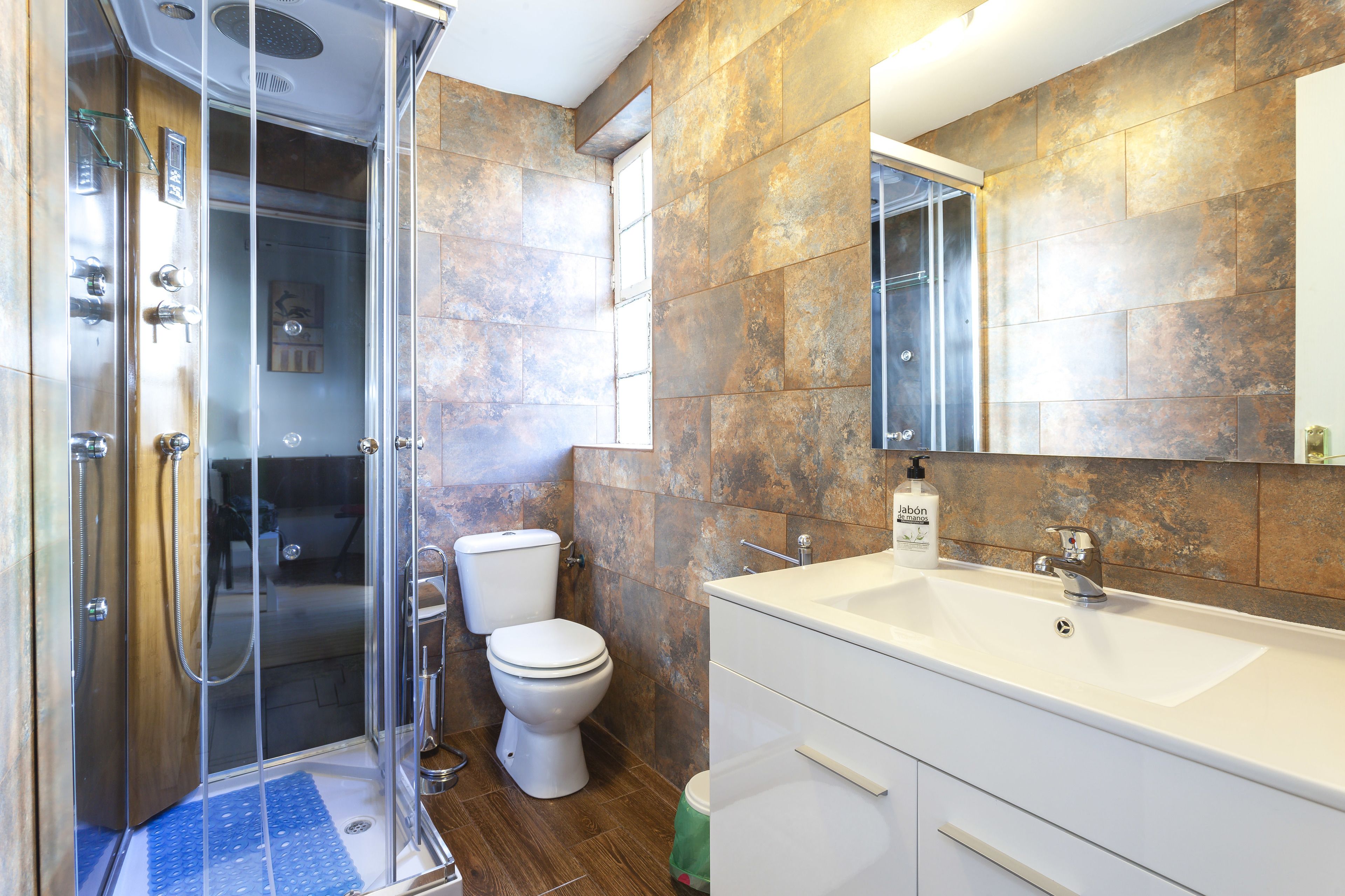 Une salle de bain moderne avec une douche à parois de verre, des toilettes et un lavabo blanc avec un miroir au-dessus.