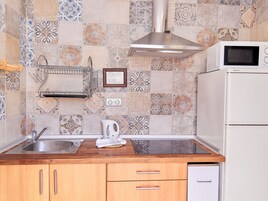 Una cocina con mostrador de madera, pileta de acero inoxidable y refrigerador blanco.
