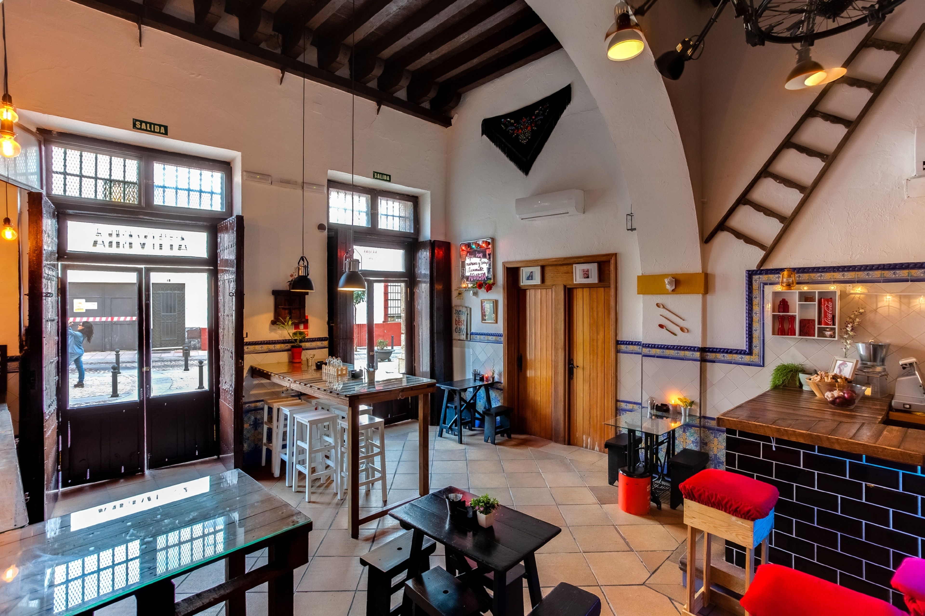 Un interior de restaurante con una zona de bar, mesas de madera y una escalera.